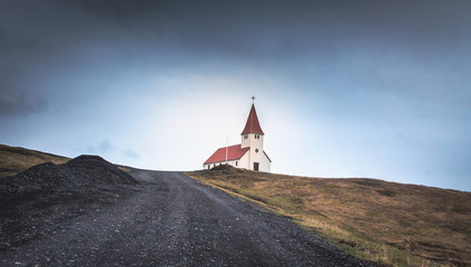 Lovely church building located near rough countryside road against cloudy sky in Iceland