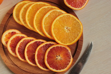 Red and orange oranges lie on the wooden plank.