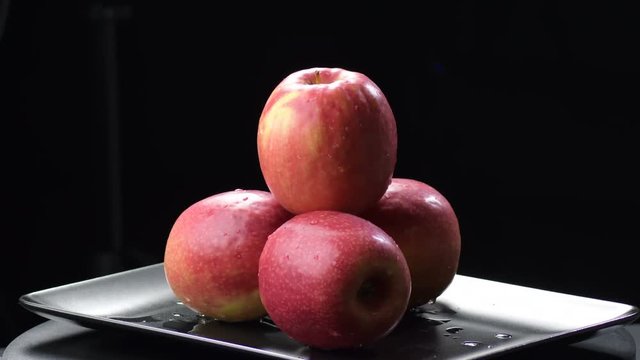 Apples fruit in a black tray gyrating on black background