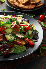 Traditional fattoush salad on a plate with pita croutons, cucumber, tomato, red onion, vegetables mix and herbs