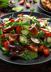 Traditional fattoush salad on a plate with pita croutons, cucumber, tomato, red onion, vegetables mix and herbs