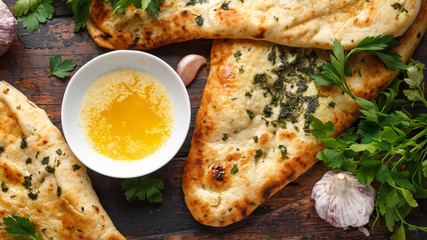 Indian naan bread with garlic butter on wooden table