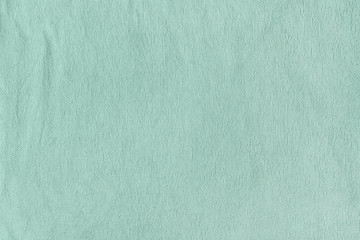 Texture of green terry towel close up. Blank light background.