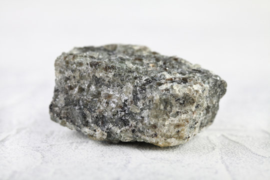 Natural mineral from geological collection - raw apatite, phosphorus ore stone from Khibiny, Kola Peninsula, Russia on white cement background.