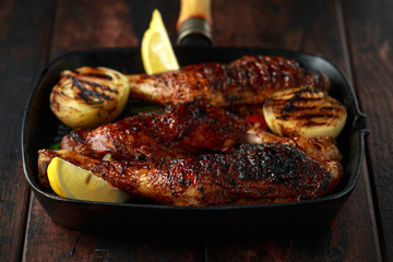 Grilled chicken legs with lemon in cast iron skillet