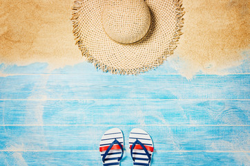 Top view of sandy beach with blue marine planks frame and summer accessories. Background with copy...