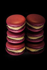 three berry macaroons with yellow filling on black background