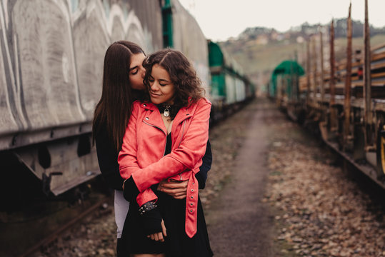 Long haired man hugging and kissing woman near train