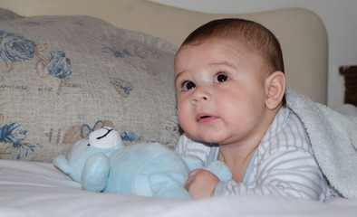 cute 4 months old baby boy having tummy time and making funny faces