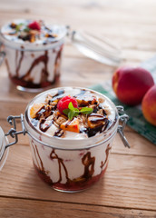 Peach parfait with yogurt, granola and chocolate topping in a jar