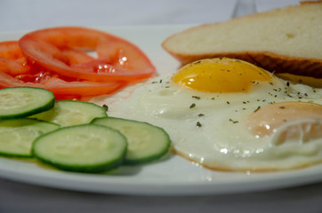 fried chicken eggs with fresh vegetables and bread. Traditional breakfast