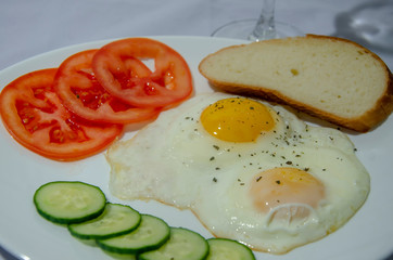fried chicken eggs with fresh vegetables and bread. Traditional breakfast