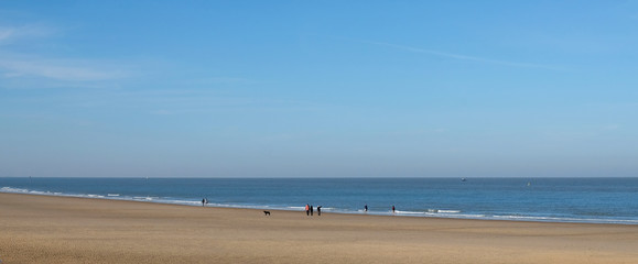 people walk along the sandy beach