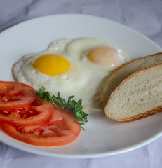fried chicken eggs with fresh vegetables and bread. Traditional breakfast