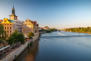 Fototapeta na wymiar Vltava river and waterfront of the old town with the theater in Prague at sunrise, Czech Republic, Europe.