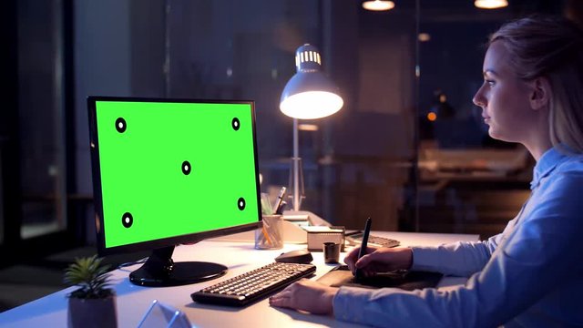 technology, virtual effects and business concept - businesswoman or graphic designer with chroma key green screen on computer monitor and pen tablet working at night office