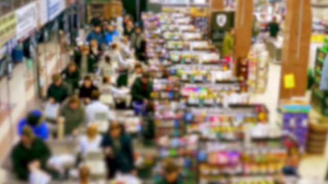 Cashier at supermarket / Retail checkout / Paying groceries. Unrecognizable buyers with carts move in queues to pay for purchases at the supermarket cashier.
