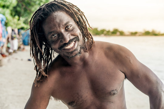 Cheerful shirtless African American male looking at camera on blurred background in Jamaica