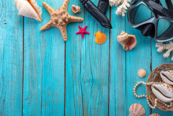 Diving mask with starfish and shells on old blue wooden background. Top view. Flat lay.