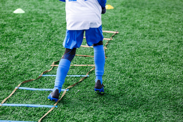Boys in white and blue football sport form make exercises on green field. Football for children, active lifestyle. Training dribble skills.