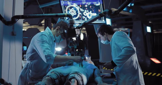 Young surgeon studies the insides of an alien creature. Laboratory technician records these operations. Operational unit of the space laboratory.