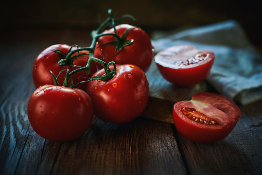 Closeup bunch of wet ripe tomatoes placed near napkin on lumber tabletop