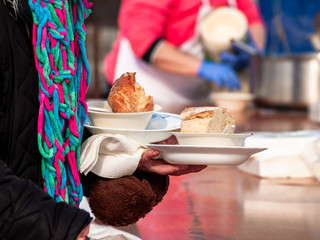 A person eating on the street in a paper plate with a plastic fork at a party