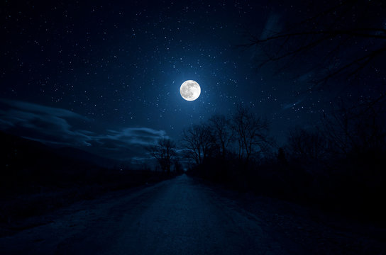 Mountain Road through the forest on a full moon night. Scenic night landscape of dark blue sky with moon. Azerbaijan