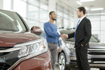 Fototapeta na wymiar Handsome African man shaking hands with car dealer after buying an auto