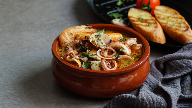 Soup of octopus and shrimps near toasts and spoon
