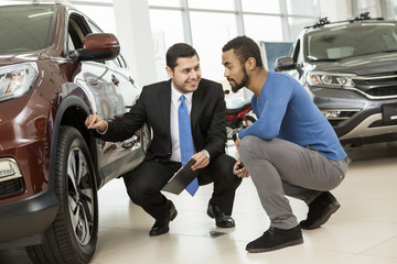 Young African man buying a car from a professional salesman
