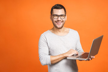 Confident business expert. Confident young handsome man in casual holding laptop and smiling while...