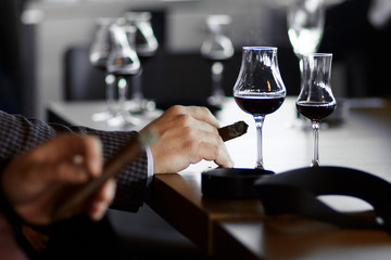 men's hands with a cigar and  glasses of mulled wine and champagne