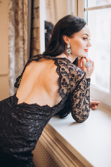 Close up indoors portrait of young gorgeous sexy elegant lady in black lace fashion dress in diamonds jewelery