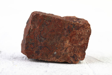 Natural mineral - red jasper from Orsk, Ural, Russia on white cement background.