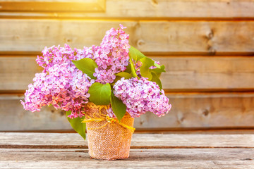 Ecology nature springtime concept. Bouquet of flowers beautiful smell violet purple lilac in vase on rustic wooden background. Inspirational natural floral spring blooming garden or park