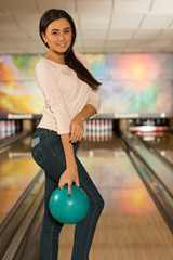 Beautiful young woman posing with a ball at the bowling club