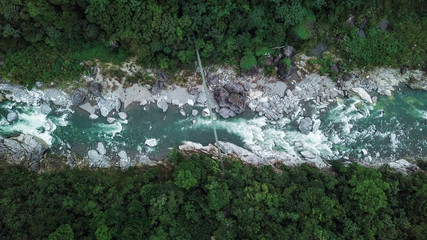 Suspension bridge over Rio Cangrejal river in Pico Bonito National Park. Top down aerial drone...