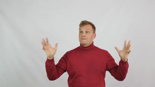 Young handsome man in red sweater posing for the camera. Handsome emotional man. A young man expresses different emotions. Emotions face and handsome hands