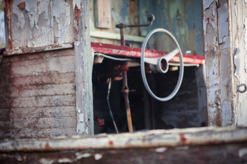 old steering wheel of a small wooden boat. The color leaves off and gets an interesting vintage look