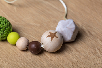 Handmade artisan wooden chain pacifier on a wooden background