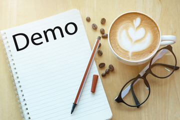 Demo concept on notebook with glasses, pencil and coffee cup on wooden table. Business concept.on...