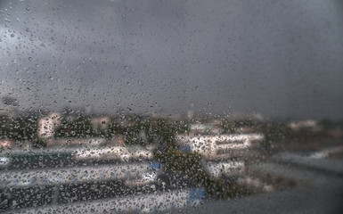 Window overlooking the spring-summer rainy city. Glass with fine drops on it. Stock background, photo