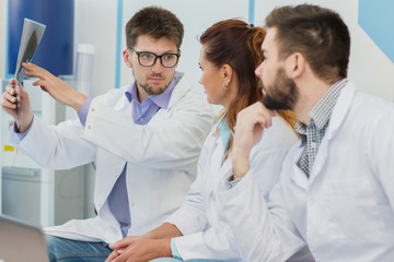 Three doctors examining x-ray at the hospital