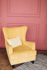 Yellow comfortable chair on pinh background. Interior concept