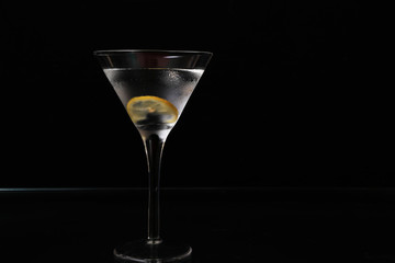 Martini in chilled glass with lemon twist on black background