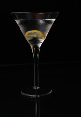 Vertical image of martini in chilled glass with lemon twist on black BG