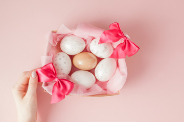 White Easter eggs in a nest on pink background. Design pastel tone in minimal flat lay