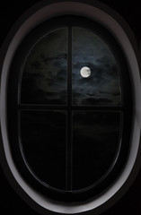 view of dark clouds, full moon through the oval window