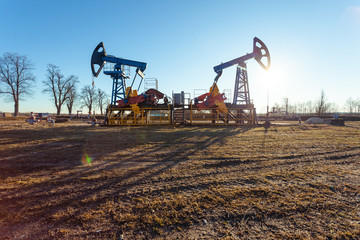 Fototapeta premium oil production tower while working in backlight against a blue sky